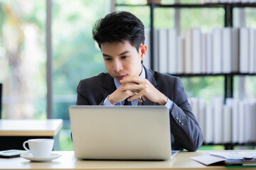 Confused ethnic male entrepreneur working on laptop in office