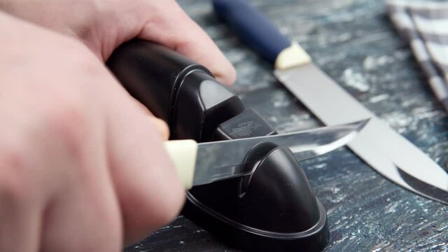 man sharpening a knife on a grindstone in the kitchen, mans work