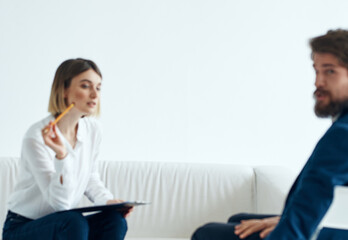 Obraz premium A business man in a suit is gesturing with his hands and a woman is sitting on the couch