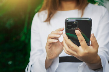 Hand of woman using smartphone on green background, Space for text or design.
