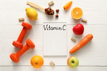 Naklejka na ściany i meble Healthy products, dumbbells and notebook with text VITAMIN C on light wooden background