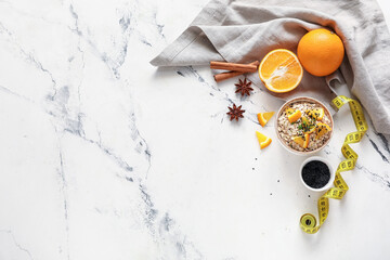 Bowl with raw oatmeal, oranges and chia seeds on light background