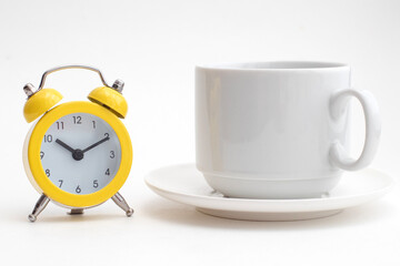 Yellow alarm clock and a white cup of coffee
