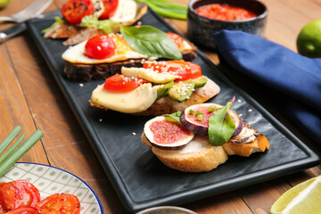 Slate plate with tasty bruschettas on wooden background