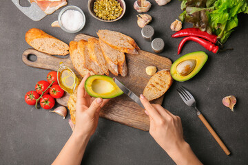 Woman preparing tasty bruschettas on dark table