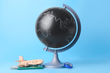 Globe with wooden airplane and passport on color background