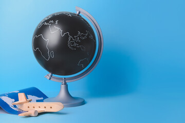Globe with wooden airplane and world map on color background