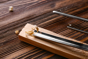 Wooden bar with chisel and saw dust on table