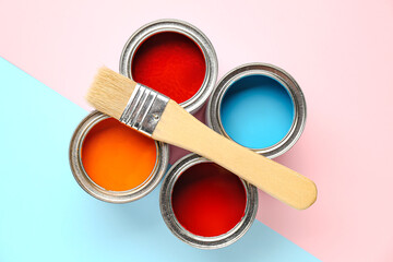 Cans of paints and brush on color background