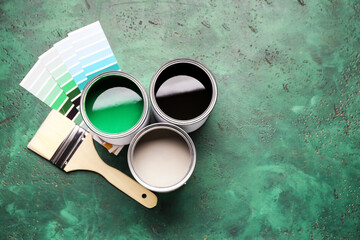 Cans of paints with palette samples and brush on color background