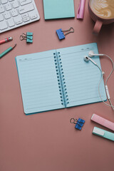 Above view of empty notebook and stationery on pink pastel background.