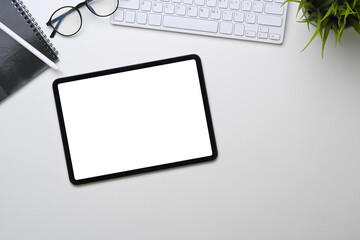 Above view of digital tablet with empty screen on white office desk.