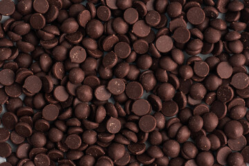 Background texture chocolate drops, close up. Chocolate pieces for dessert decoration.