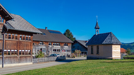 kleine Holzkapelle zwischen alten, traditionellen Bauernhäusern