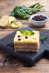 Banana sponge cake with nuts and chocolate drops. Delicious sweet dessert for tea, wooden background.