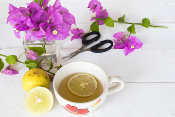 mix honey lemon herbal hot healthy drinks for sore throat ,teapot with lemon slice and purple flowers bougainvillea  on background white