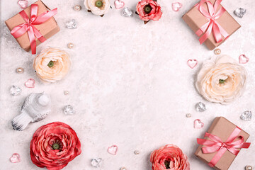 Festive romantic background with peony flowers, gift and hearts on light marble. Frame top down composition with copy space.