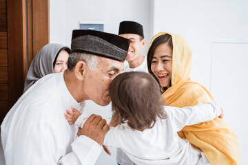 Happy asian muslim aged couple meeting kids and grand children at doorstep during eid mubarak celebration