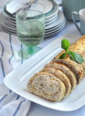 baked minced turkey meat roll with cheese and herbs side view on served dinner table background closeup. Selective focus