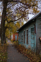 Fototapeta na wymiar Autumn in a small town. Old wooden house in the village. Gloomy and overcast day. A deserted street in the Russian outback. Emptiness on an abandoned street during a pandemic