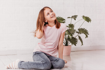 Cute teenage girl sits in a light room and dreams