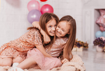 Two happy laughing girls cuddle and play in a light room