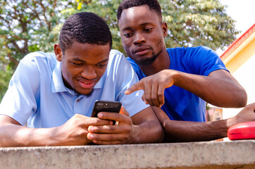 two handsome african feeling excited about what they saw on their cellphone