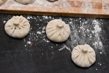 Raw Georgian khinkali crushed by flour lying on the corner of a kitchen table