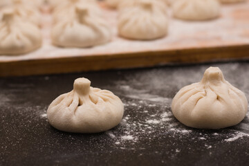 Focused image of raw khinkali on a wooden board side view.