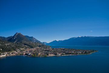 Naklejka na ściany i meble Panoramic view of the historic city of Toscolano Maderno on Lake Garda Italy. Aerial view of the town on Lake Garda. Tourist place on Lake Garda in the background Alps and blue sky.