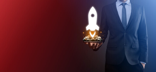 Startup business concept, Businessman holding tablet and icon rocket is launching and soar flying out from screen with network connection on dark background.