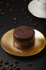 Austrian cake, sackertorte. Chocolate cake on a golden plate. White cup with cappuccino. Top view for dessert with coffee. Coffee beans on a black textured table.