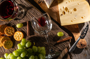Different types of cheeses, cheese tasting with grapes and crackers and glasses of red wine, top view