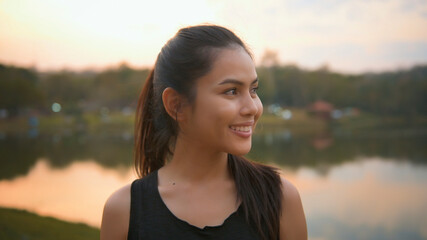 Portrait of a young sporty woman is smiling nature outdoor at sunset