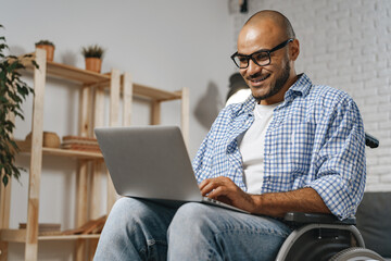 Disabled man sitting in a wheelchair and using laptop