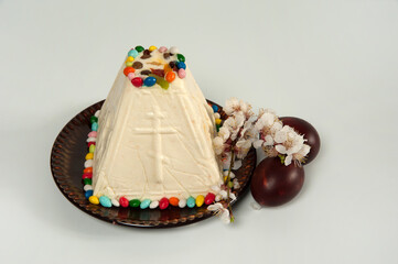 Easter composition. Eggs, apricot flowers and Orthodox Easter curd dessert in the form of a pyramid close-up on a pastel gray background. Happy Easter Holidays. Selective focus.