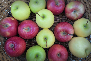 red, green and yellow apples in a wicker basket top view