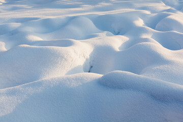 Snowy wavy texture with harsh blue shadows. Sunset