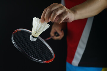 A badminton player postures the face of the racket to serve the badminton ball in the match