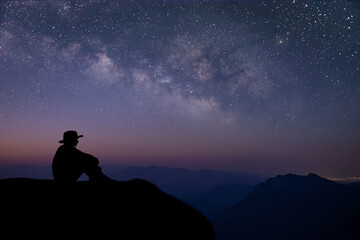 Silhouette of young traveler sitting and watched the star and milky way on top of the mountain...