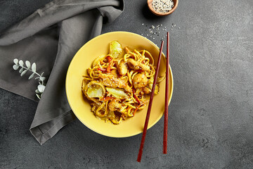 Curry Udon Noodles. Asian curry udon in yellow plate with wooden chopstick on dark slate table....