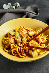Curry Udon Noodles. Asian curry udon in yellow plate with wooden chopstick on dark slate table. Asian, authentic food concept