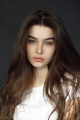 Fototapeta premium Close-up portrait of a young beautiful woman, on a dark background. Beauty portrait of a girl, studio tests.