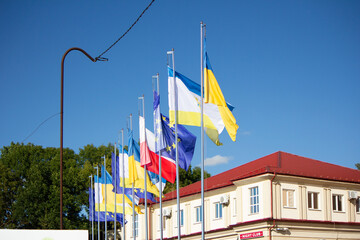 Row of European flags on a background of sky and city
