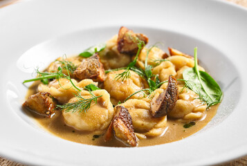 Dumplings Food Restaurant Plate. Dumplings With Creamy Porcini Sauce. White restaurant plate on white table. Rustic restaurant food concept.