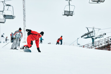 Male snowboarder in a red suit rides on the snowy hill with snowboard, Skiing and snowboarding concept