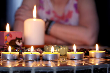 Fortune telling session, seeing the destiny and astrology. Woman foreteller sitting at round table with candles and tarot cards