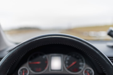 Obraz na płótnie Canvas Car steering wheel dashboard on a blurry landscape.Front view picture.