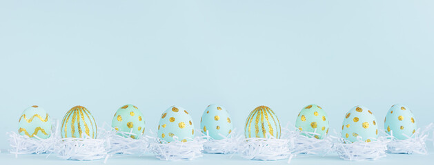 Stylish easter banner - blue easter eggs with gold design in white nest in row on blue background.