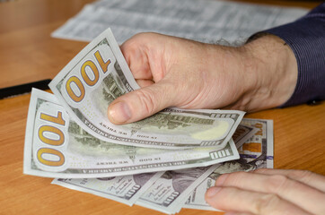 Hands of a male with dollars in close-up.